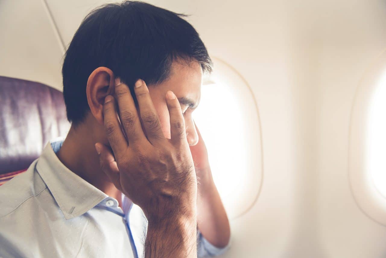 Man experiencing ear discomfort on a flight.