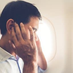 Man experiencing ear discomfort on a flight.