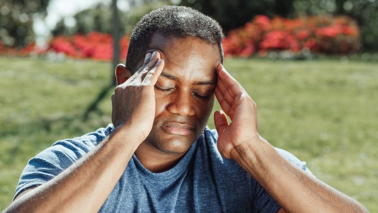 Man experiencing a headache rubbing his temples.