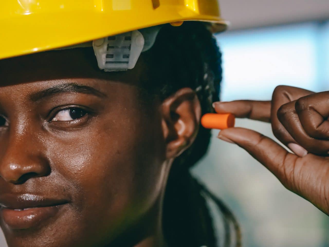 Female construction working putting in earplugs to protect her hearing.