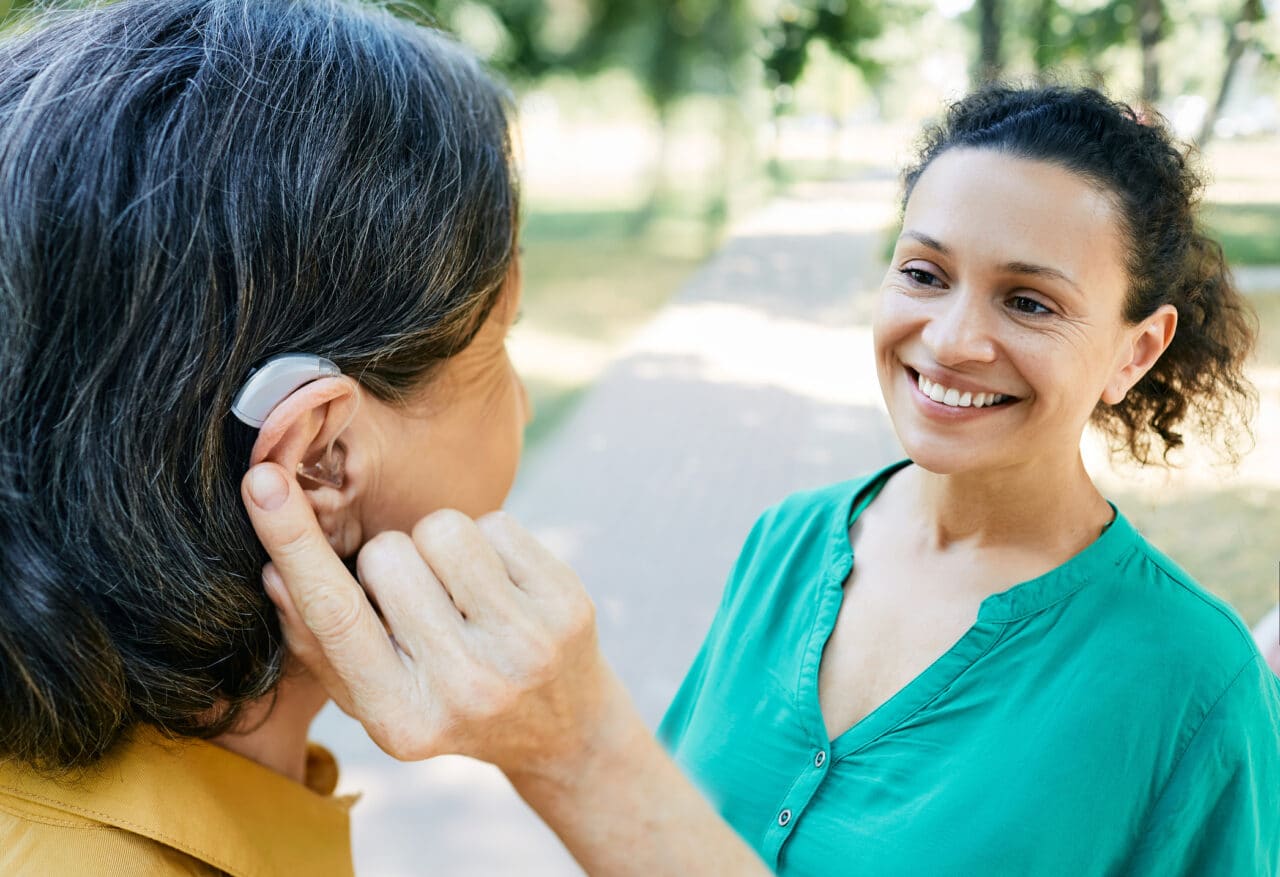 Woman with a hearing aid chatting with a friend outside.