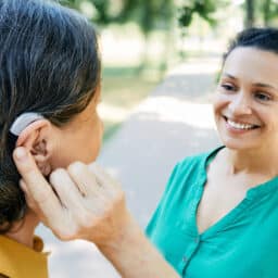 Woman with a hearing aid chatting with a friend outside.