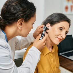 Older woman receiving an ear exam.