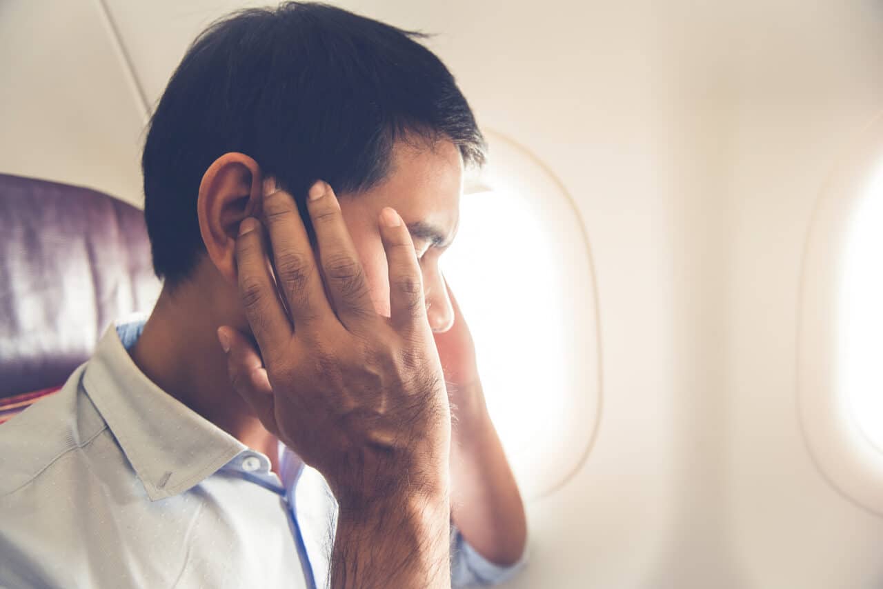 A man experiencing ear pain on a flight.