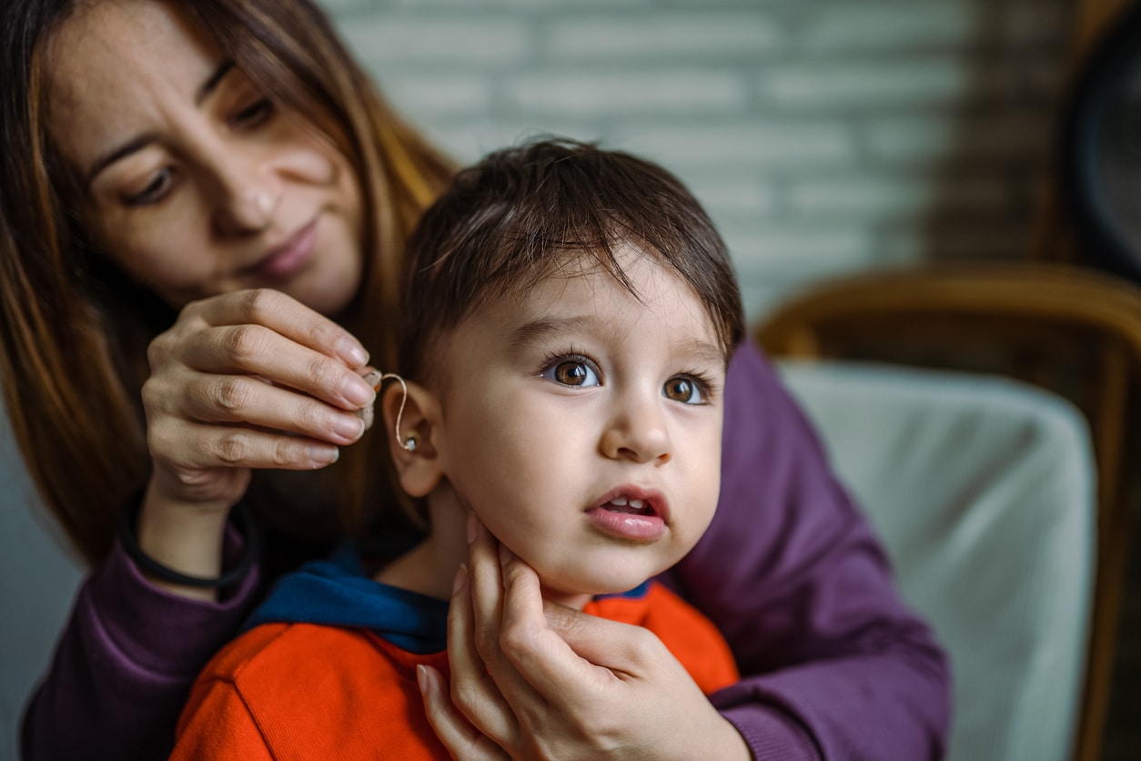 mother placing a hearing aid in the ear of a small child