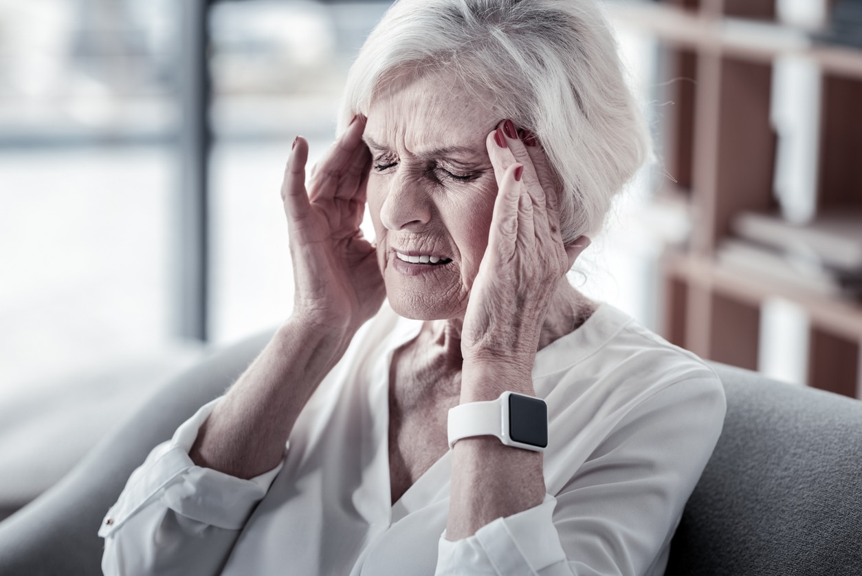 Woman with worsening tinnitus holding her temples.