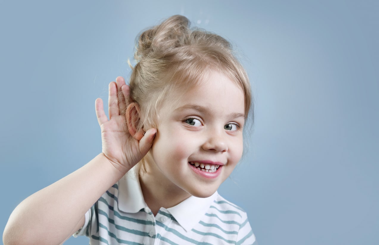 Young girl with a hand to her ear listening.