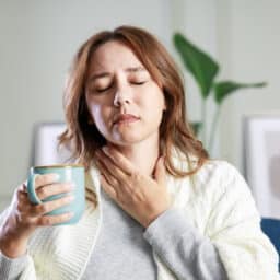 Woman with a sore throat holder a mug of tea