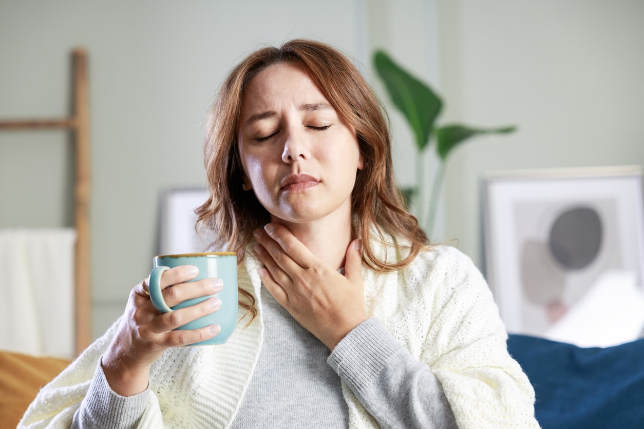 Woman with a sore throat holder a mug of tea.