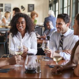 Four friends drinking wine in a busy restaurant