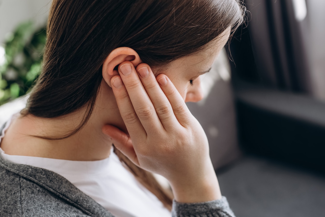 Woman holding her right ear.