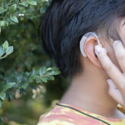 Boy touches hearing aids outside